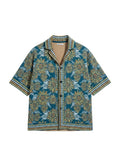 Thingy men's short-sleeve collared shirt with a teal base and a bold yellow floral print. Features a textured knit and geometric trim.
